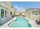 A backyard pool with clear water, surrounded by a white fence and a patio with furniture, with some green grass on the side at 7544 Gathering Dr, Kissimmee, FL 34747