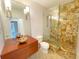 Elegant bathroom with a walk-in shower, stone tile, and modern vanity at 7580 Toscana Blvd # 834, Orlando, FL 32819
