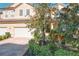 Tan three-story townhome with two-car garage, landscaping, and brick driveway at 8737 The Esplanade # 65, Orlando, FL 32836