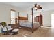 Well-lit main bedroom with a four-poster bed, ceiling fan, wood-style flooring, and baby chair at 15937 Birchwood Way, Orlando, FL 32828