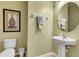 Clean powder room with pedestal sink, toilet, and framed art at 2616 Santosh Cv, Kissimmee, FL 34746