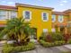 Bright yellow two-story townhome with landscaping and palm trees at 4765 Ormond Beach Way, Kissimmee, FL 34746