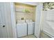 Well-lit laundry room with washer, dryer, and shelving at 142 Sandy Point Way, Clermont, FL 34714