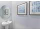 Small bathroom with pedestal sink, framed art, and circular mirror at 1521 Isleta Loop, Kissimmee, FL 34741