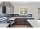 Modern kitchen features dark cabinetry, quartz countertops, and stainless steel appliances at 1933 Burgundy Dr, Minneola, FL 34715