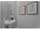 Clean and simple bathroom with pedestal sink, mirror, and botanical wall art at 3338 Private Oak Dr, Apopka, FL 32703