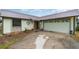 Front view of a charming light green house with a metal roof and attached garage at 628 Twin Oaks Cir, Daytona Beach, FL 32117