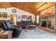 Living area featuring a wood-paneled ceiling, stone fireplace, and leather sofas at 628 Twin Oaks Cir, Daytona Beach, FL 32117