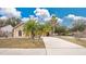 Tan house with palm trees, a large driveway, and a neatly landscaped yard at 905 Hatteras Ave, Minneola, FL 34715