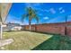 A view of the backyard with a lush green lawn, a mature palm tree, and a brick privacy wall at 10812 Woodchase Cir, Orlando, FL 32836