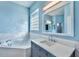 Bright bathroom featuring a soaking tub, vanity with sink, and a glass block window for natural light at 10812 Woodchase Cir, Orlando, FL 32836