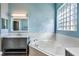 Relaxing bathroom with a soaking tub, decorative glass block window, and stylish vanity at 10812 Woodchase Cir, Orlando, FL 32836