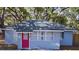 Charming light blue house with red door, surrounded by lush trees at 1338 S Elliott St, Sanford, FL 32771