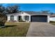 White house with black accents, a two-car garage, and a landscaped lawn at 1613 Lansfield Ave, Deltona, FL 32738