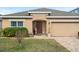 One-story house with tan exterior, American flag, and landscaped front yard at 2204 Napone Ln, Minneola, FL 34715