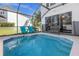 Screened-in pool with blue chairs and a wicker bench at 2546 Renshaw St, Kissimmee, FL 34747