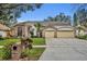 Brick house with three-car garage, manicured lawn, and mature trees at 3838 Gatlin Place Cir, Orlando, FL 32812