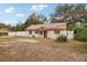 Single-story house with brown metal roof and red front door, surrounded by trees and a yard at 513 Seminole Ave, Fruitland Park, FL 34731