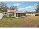 White house with brown roof, screened porch, and spacious backyard at 513 Seminole Ave, Fruitland Park, FL 34731