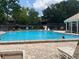 Community pool with clear blue water, surrounded by a brick patio and lounge chairs at 6073 Windhover Dr # C04, Orlando, FL 32819