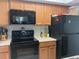 Kitchen features wood cabinets, black appliances, and a microwave at 6073 Windhover Dr # C04, Orlando, FL 32819