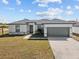 Newly built home with gray garage door and landscaped lawn at 803 Fraser Dr, Poinciana, FL 34759