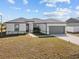 Newly built home with gray garage door and landscaped lawn at 803 Fraser Dr, Poinciana, FL 34759