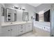 Bright bathroom featuring double vanity sinks, and a tiled tub encased by black curtains at 127 Westmoreland Cir, Kissimmee, FL 34744
