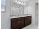 Bright bathroom with a double vanity, wood cabinets, granite countertop, and a large mirror at 7100 Cherry Pasture Rd, Groveland, FL 34736