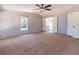 Bedroom with carpet, a ceiling fan, large windows, and access to the ensuite bathroom at 13811 County Road 109D, Lady Lake, FL 32159