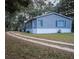 Gray manufactured home with white skirting, wooden steps, and a long driveway at 13811 County Road 109D, Lady Lake, FL 32159