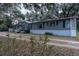 Gray manufactured home with white skirting, wooden steps, and a long driveway at 13811 County Road 109D, Lady Lake, FL 32159