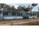 Gray manufactured home with white skirting, wooden steps, and a long driveway at 13811 County Road 109D, Lady Lake, FL 32159