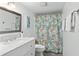 Bathroom with white vanity, marble countertop, and seashell shower curtain at 1420 N Atlantic Ave # 302, Daytona Beach, FL 32118