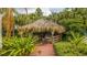Thatch-roof gazebo with tables and chairs in a lush garden setting at 702 Rum Run # 38702, Davenport, FL 33897
