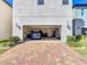 Spacious two-car garage featuring a sleek Tesla vehicle and a brick paver driveway for added curb appeal at 9317 Holliston Creek Pl, Winter Garden, FL 34787