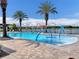 A community pool with a splash pad, lounge chairs and a fence overlooking a lake and palm trees at 14190 Dove Hollow Dr, Orlando, FL 32824