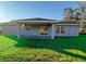 House exterior showcasing a covered patio and grassy backyard at 3 Fisher Loop Crse, Ocklawaha, FL 32179