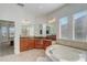 Large bathroom with corner bathtub, granite countertops, and wood cabinets at 32604 View Haven Ln, Sorrento, FL 32776