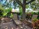 Relaxing patio furniture under a large shade tree in a beautifully landscaped backyard at 370 Silver Maple Rd, Groveland, FL 34736