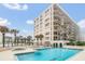 Beautiful building featuring a pool, lounge chairs, hot tub, palm trees, and ocean views at 4575 S Atlantic Ave # 6703, Port Orange, FL 32127