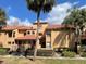 Tan two-story condo building with red tile roofs, lush landscaping, and a walkway at 4709 Capri Pl # 189, Orlando, FL 32811