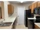 Galley kitchen with wood cabinets and black appliances at 5275 Images Cir # 306, Kissimmee, FL 34746