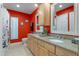 Bathroom featuring double sinks with granite countertops, complemented by eye-catching red walls at 5737 Masters Blvd, Orlando, FL 32819