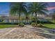 Charming home exterior with lush landscaping, brick driveway, and towering palm trees at sunset at 5737 Masters Blvd, Orlando, FL 32819