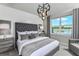 Spacious main bedroom with a tufted headboard, large window, and modern chandelier at 6375 Dew Drop Loop, St Cloud, FL 34771