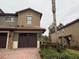 Two-story townhome with a brown garage door and well-manicured landscaping at 8973 Azalea Sands Ln # 8973, Davenport, FL 33896