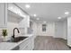 Modern kitchen with white cabinets, stainless steel sink, and gray vinyl flooring at 1703 E Fern Rd, Lakeland, FL 33801