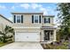 Two-story house with neutral siding, dark shutters, and a white garage door at 229 Gina Ln, Davenport, FL 33837