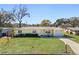 Cute yellow house with a green lawn, driveway, and mature trees at 3710 Sutton Dr, Orlando, FL 32810